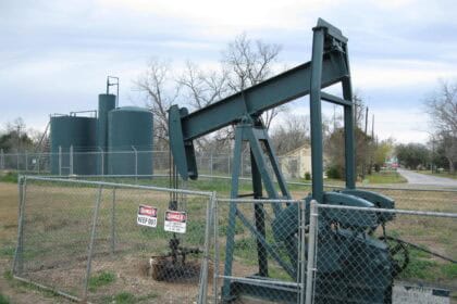 Oil pumpjack operating on rural landscape under blue sky