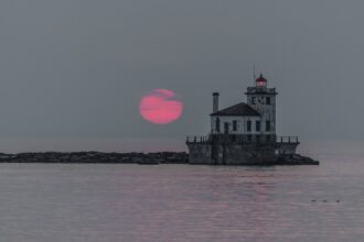 Aerial panoramic view of the Lake Ontario shoreline and Oswego Harbor lighthouse amid U.S. and Canada bilateral maritime boundary debates.