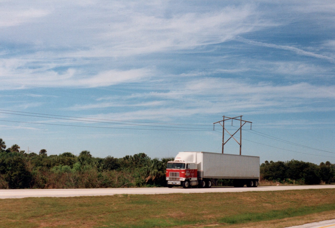 A heavy commercial diesel semi-truck hauling freight along an American interstate highway.