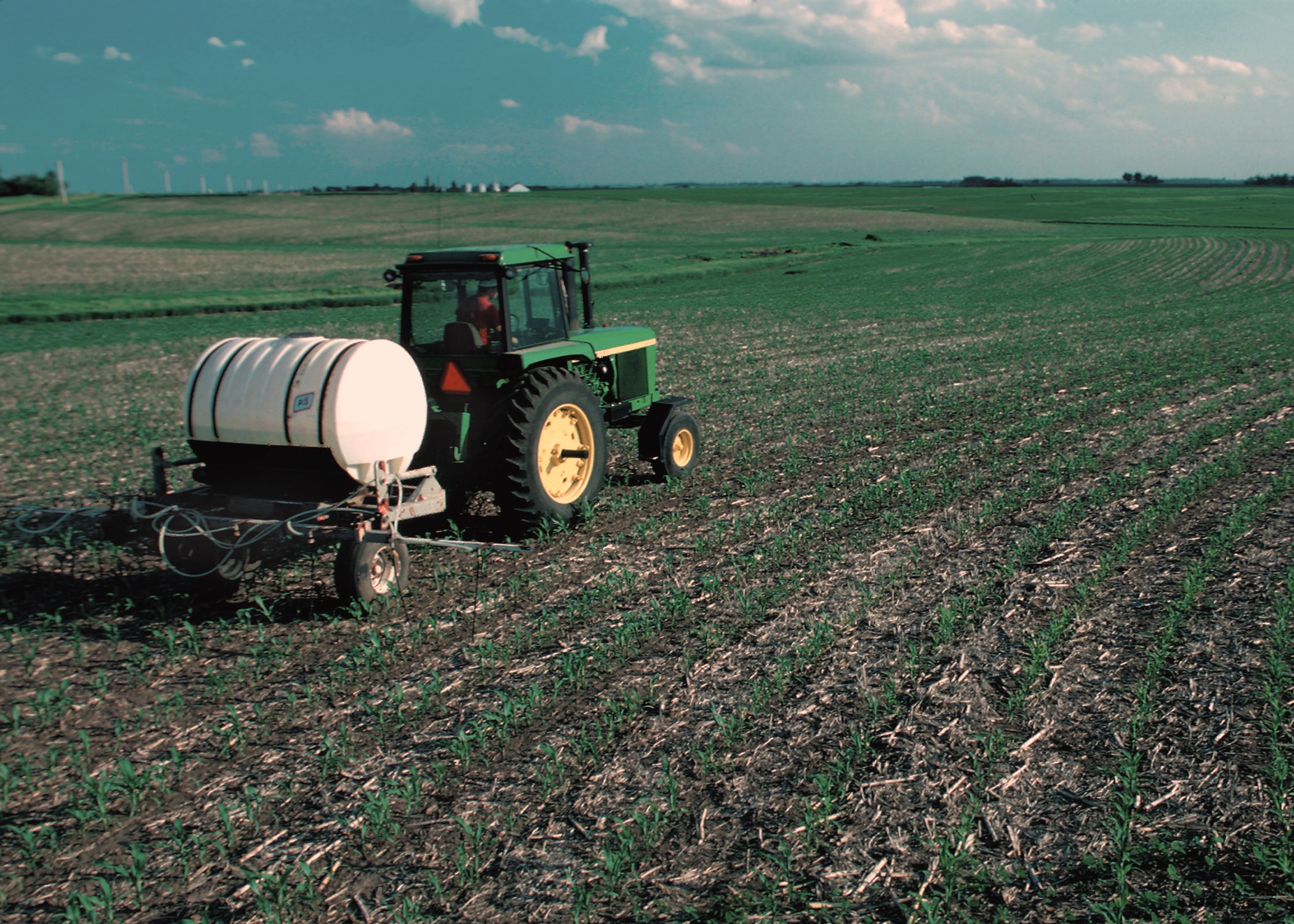 Agricultural equipment applying treatments to commercial corn field