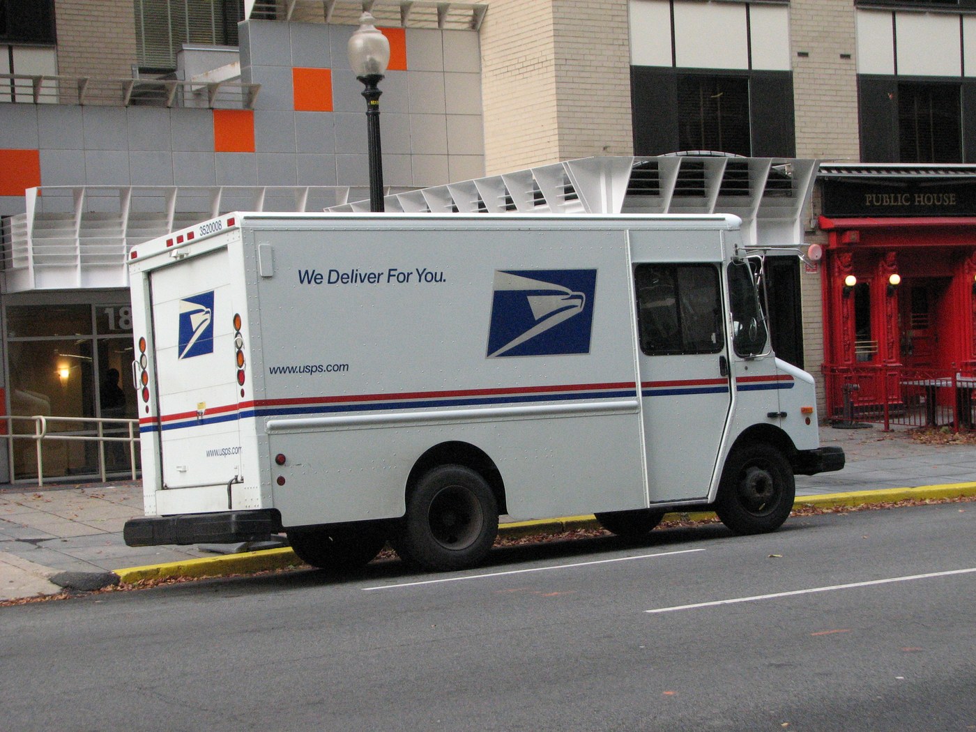 A United States Postal Service delivery vehicle on a city street carrying election mail and packages.