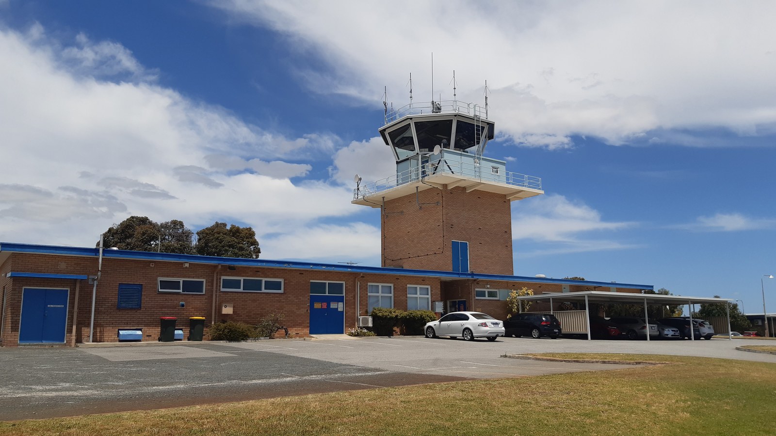 Exterior view of an airport air traffic control tower overseeing flight operations beneath a clear blue sky