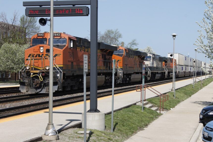 Four BNSF diesel-electric locomotives pulling a long intermodal freight train along a mainline corridor