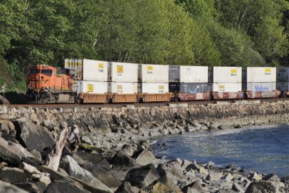 A diesel locomotive hauling commercial freight railcars along an interstate rail corridor