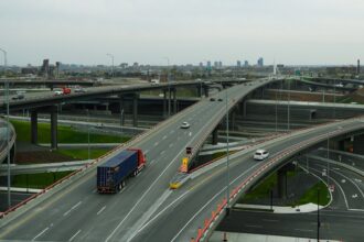Heavy commercial semi-truck and trailer traveling across an interstate highway bridge