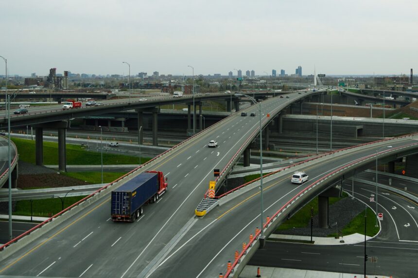 Heavy commercial semi-truck and trailer traveling across an interstate highway bridge