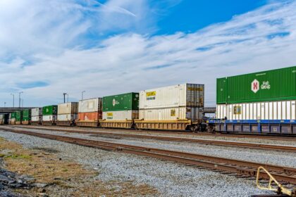 Freight train loaded with intermodal shipping containers moving along commercial rail corridor
