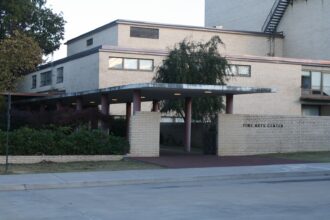 Brick academic building and tree-lined lawn on a public state university campus